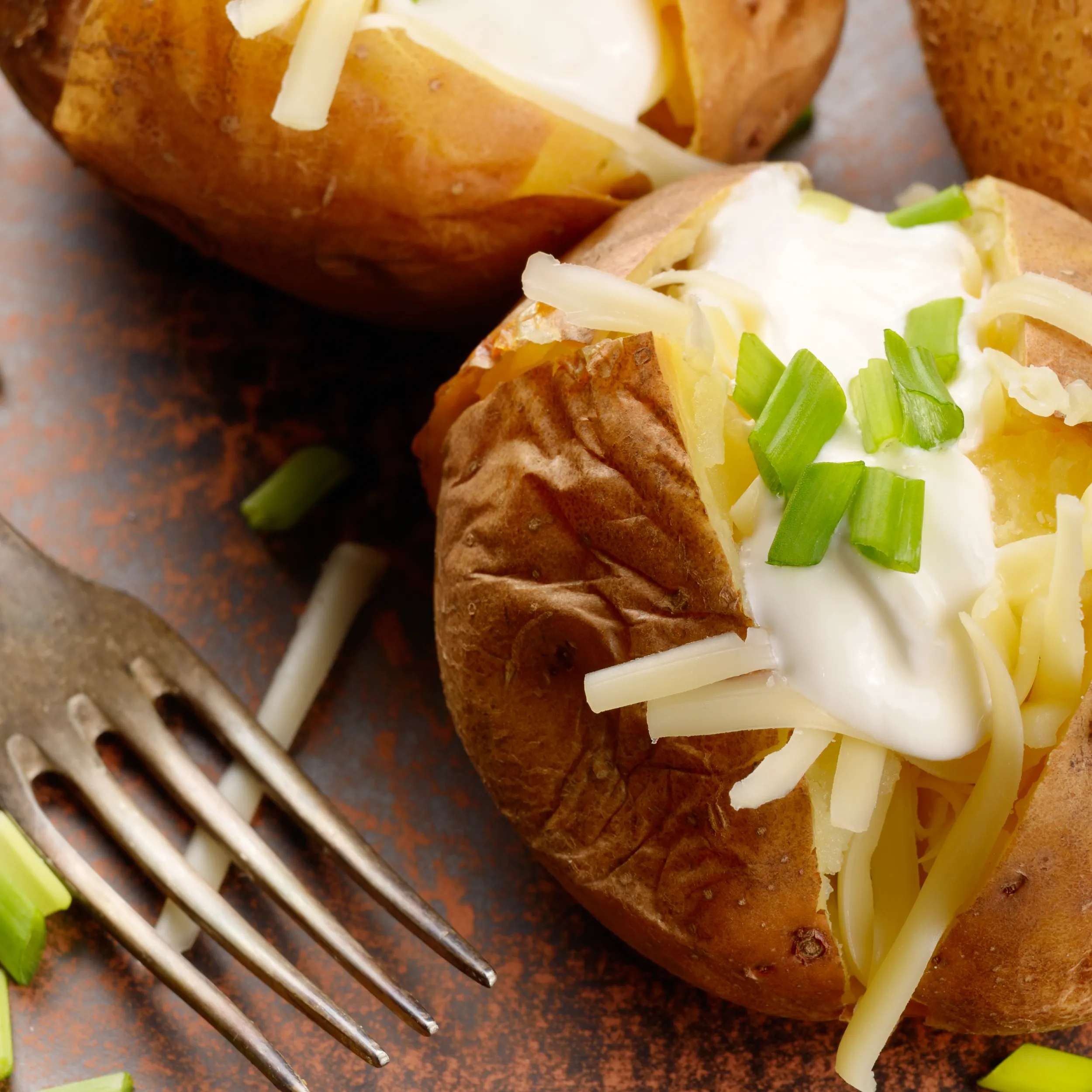 A baked potato topped with a dollop of fresh sour cream and chives